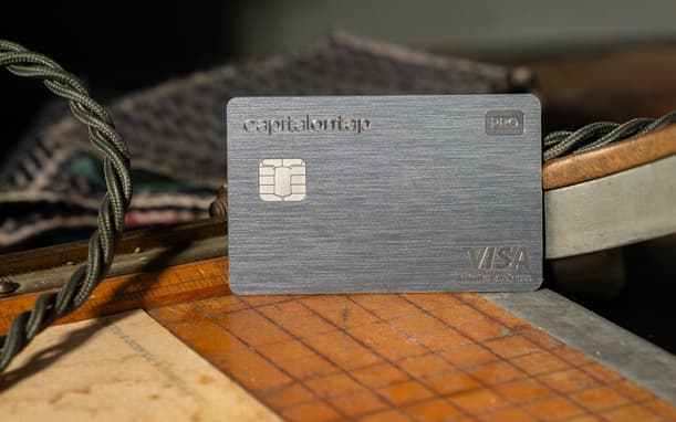 Capital On Tap Pro Metal Visa Card Resting On A Wooden Ruler At A Workbench, With Braided Cord And Fabric In The Background
