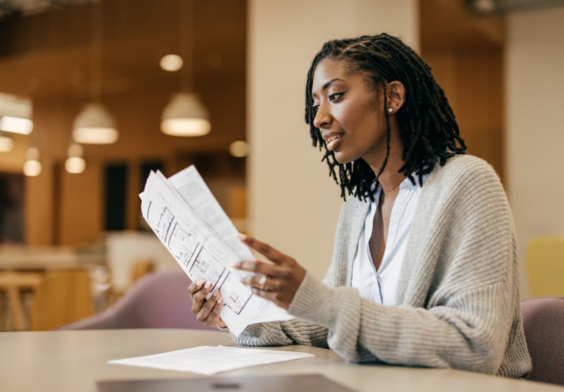 Female Small Business Owner Sitting At A Table Looking Over Paperwork