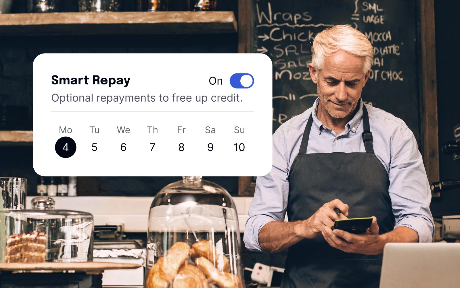 A Baker Standing Behind A Counter Smiling At His Phone, With An Overlay Of The Smart Repay Feature UI.