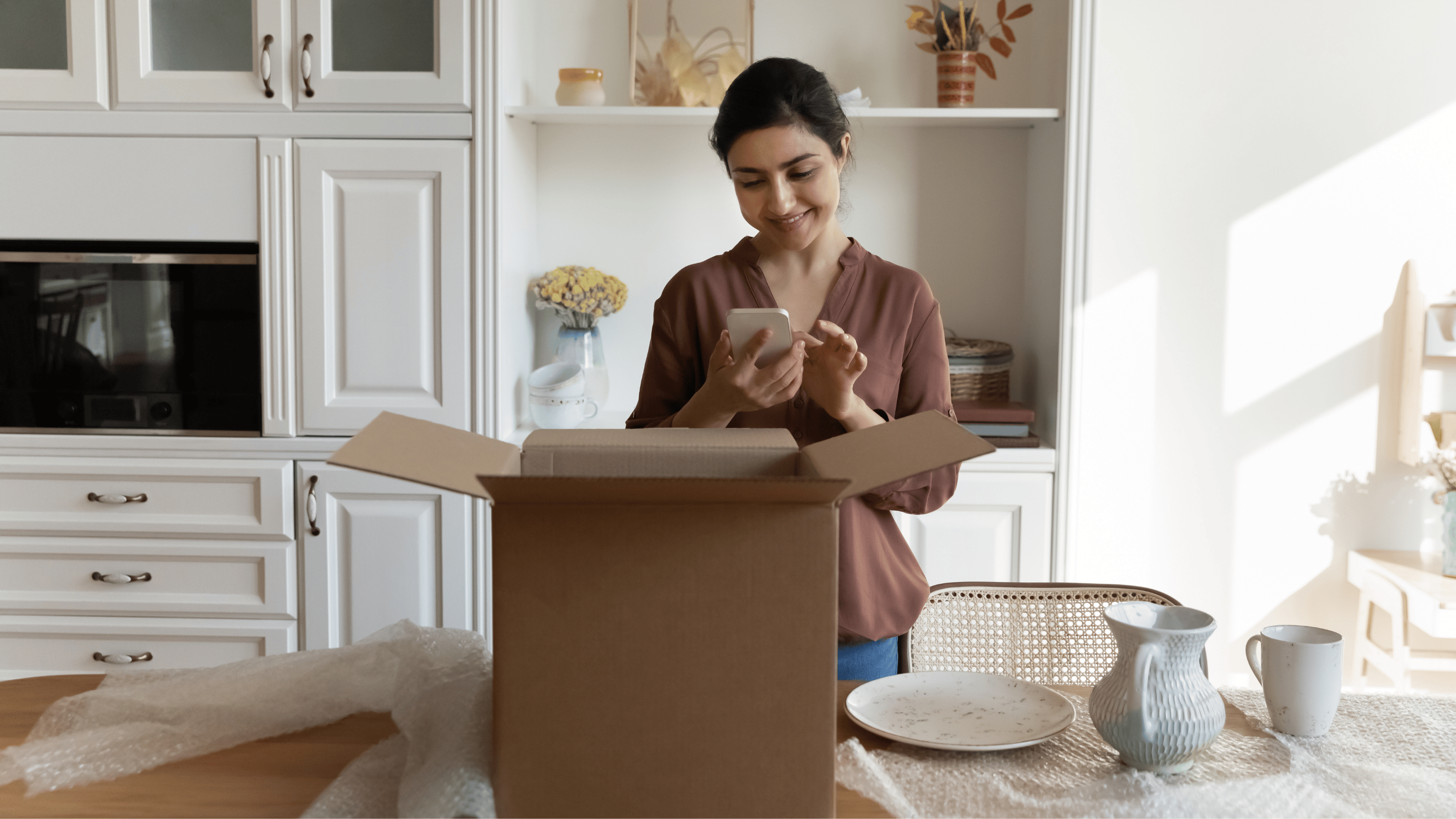 Woman Smiling Standing In Front Of Open Parcel Using Phone To Leave A Review
