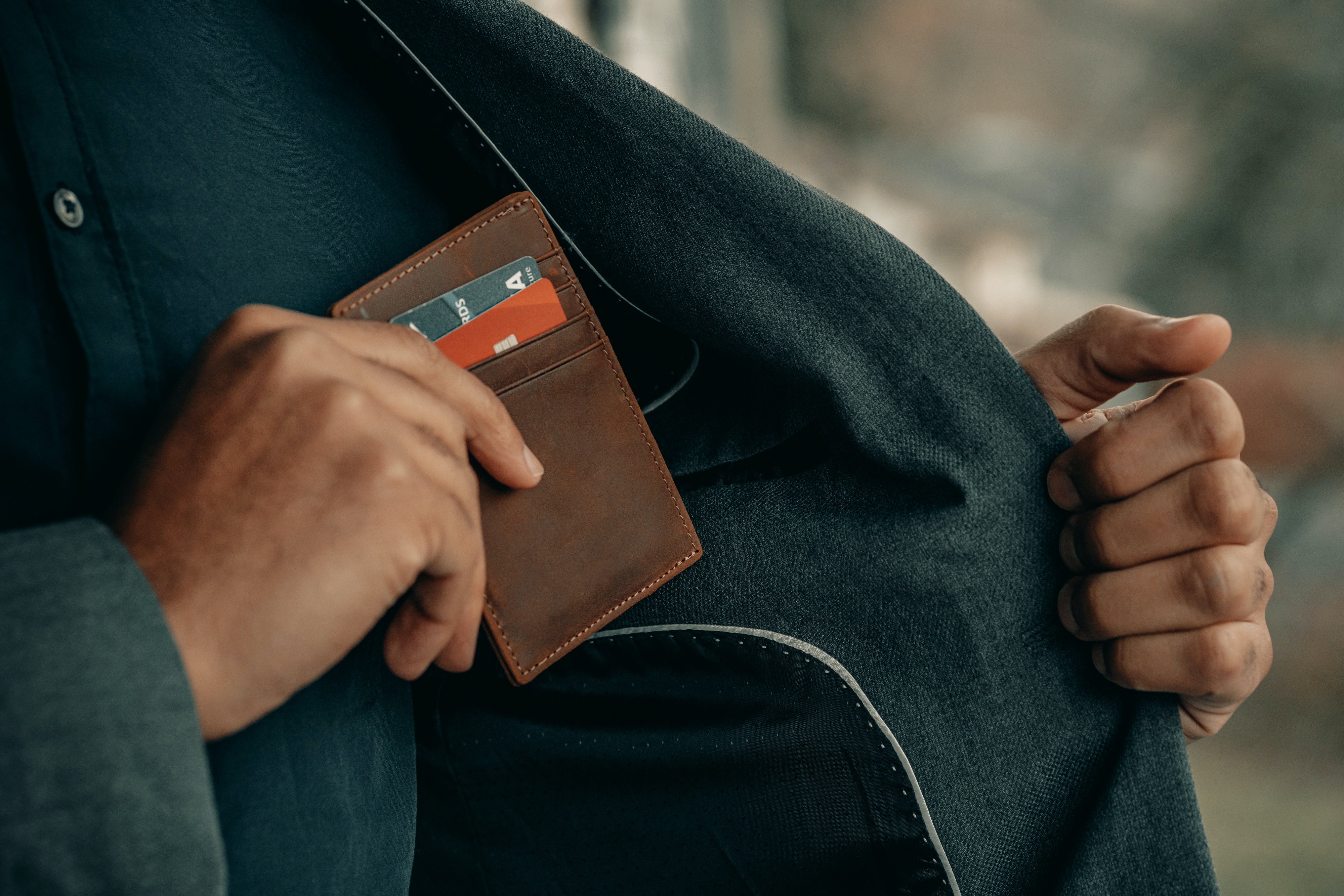 Man putting wallet that holds credit cards in the pocket of his jacket