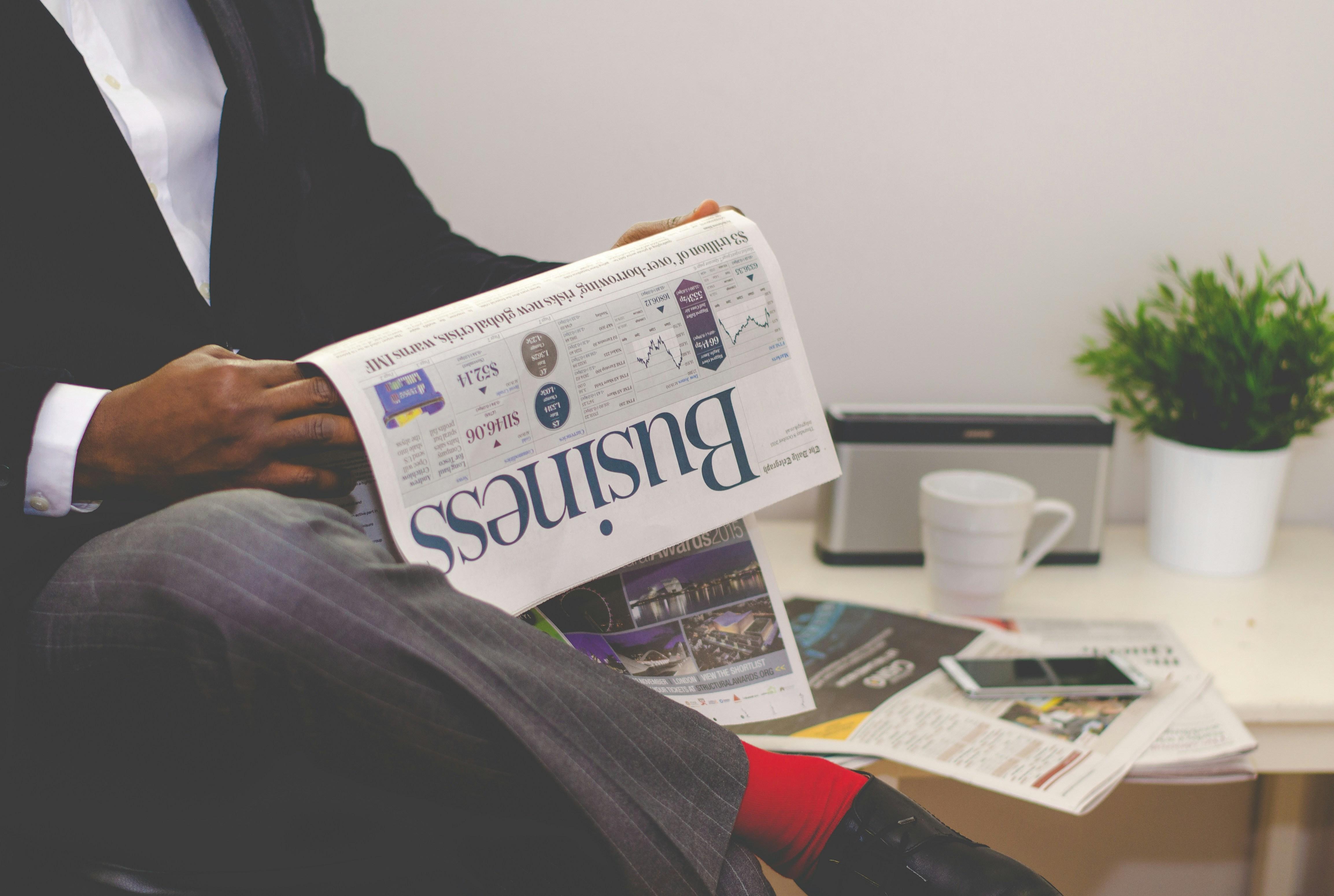 A Man Reading Business Insights In A Newspaper