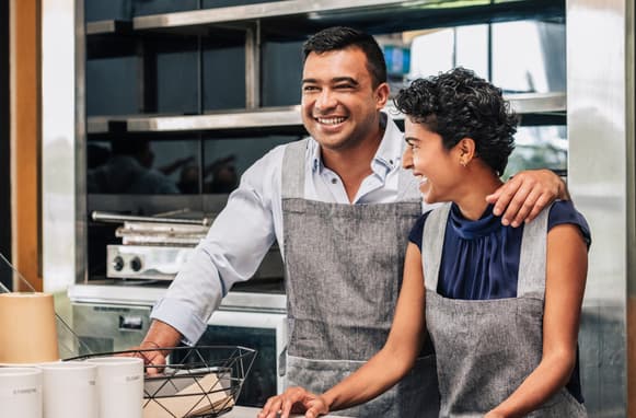 Husband And Wife Coffee Shop Owners Laughing Together