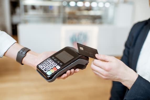 Person In A Suit Paying At A Card Terminal Using A Black Card