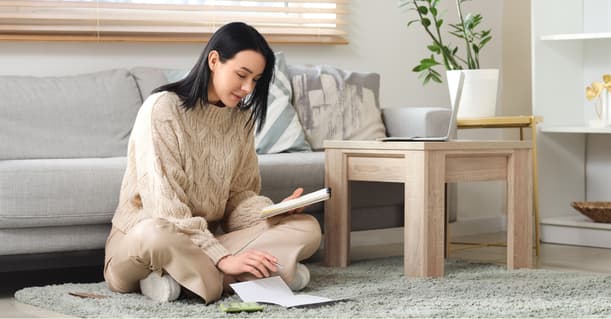 A Female Business Owner Sitting On The Floor With Some Papers And A Calculator