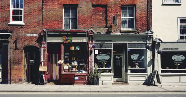 A Red Brick Building With Two Shop Fronts, A Vintage Store And A Cafe.