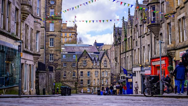 Edinburgh High Street Lined With Shops And Colourful Bunting Overhead