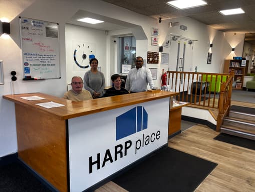 The Harp Place Team Standing Behind The Front Desk Smiling
