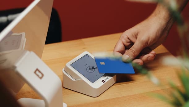 A Closeup Of Someone Paying Using A Blue Card