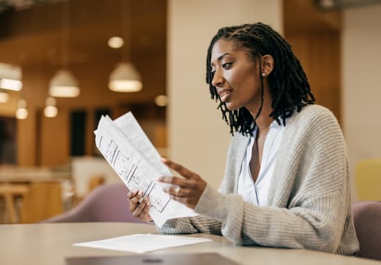 Female Small Business Owner Sitting At A Table Looking Over Paperwork