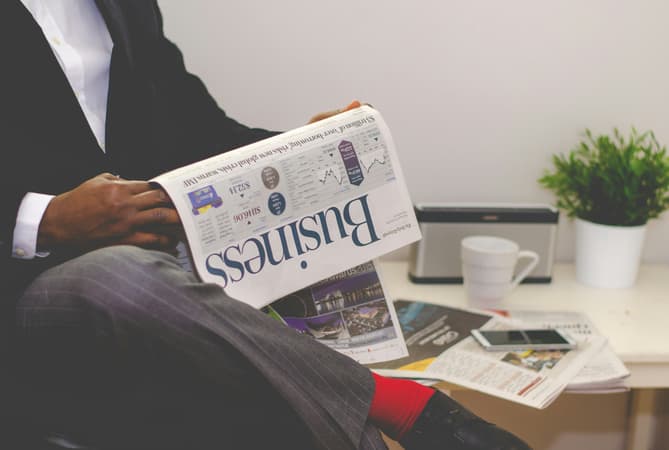 A Man Reading Business Insights In A Newspaper
