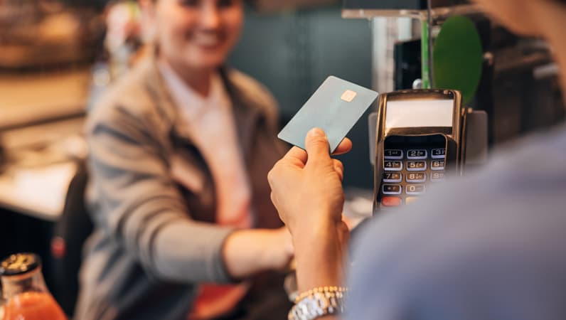 A Close Up Of Someone Paying On A POS Machine Using A Black Card
