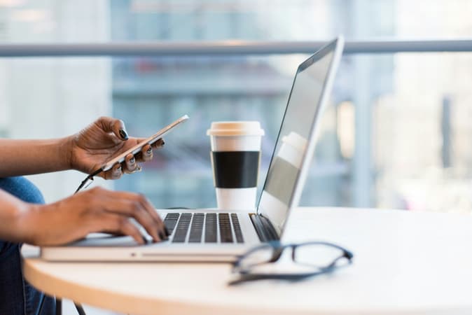 Woman Using Laptop And Mobile Phone