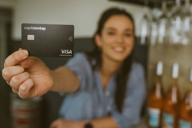 Woman In Wine Shop Holding Capital On Tap Business Credit Card