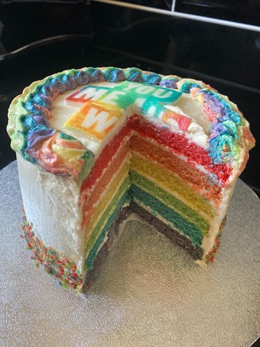 A cake with a slice missing to show the inside. There are 6 layers, each are a different colour